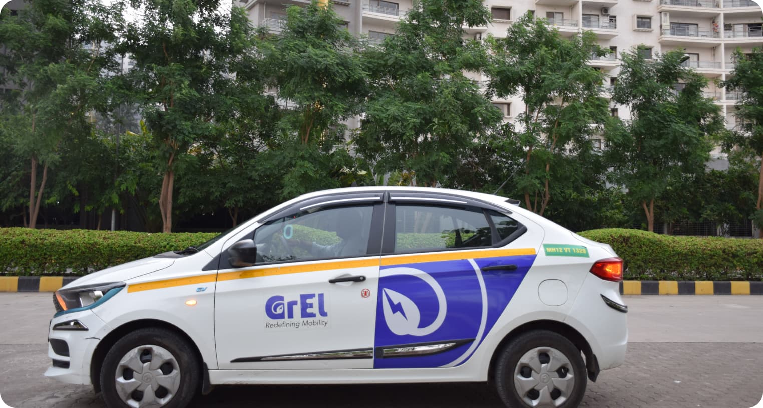 Side view of a white Tata Tigor EV in GrEL livery