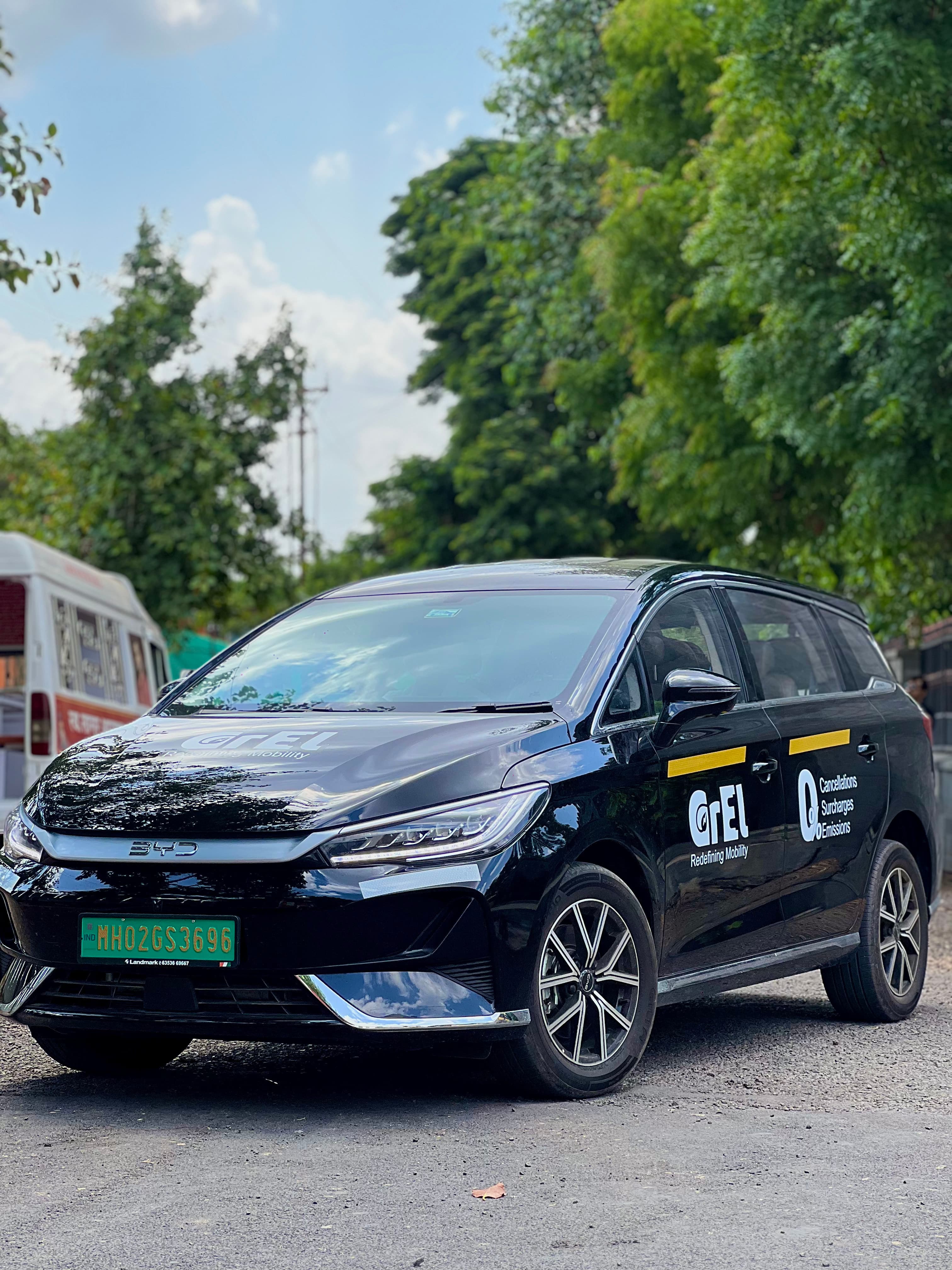 A black BYD eMAX 7 in GrEL branding on a tree-lined road